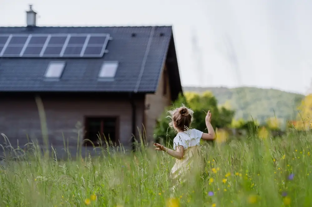 Residential home with rooftop solar panels and child playing in the yard