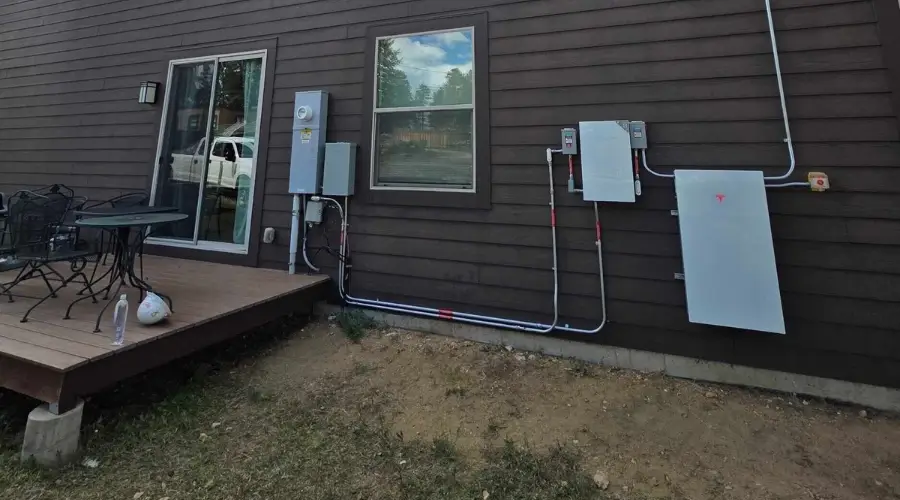 Tesla Powerwall battery storage system with electrical equipment mounted on a residential exterior wall